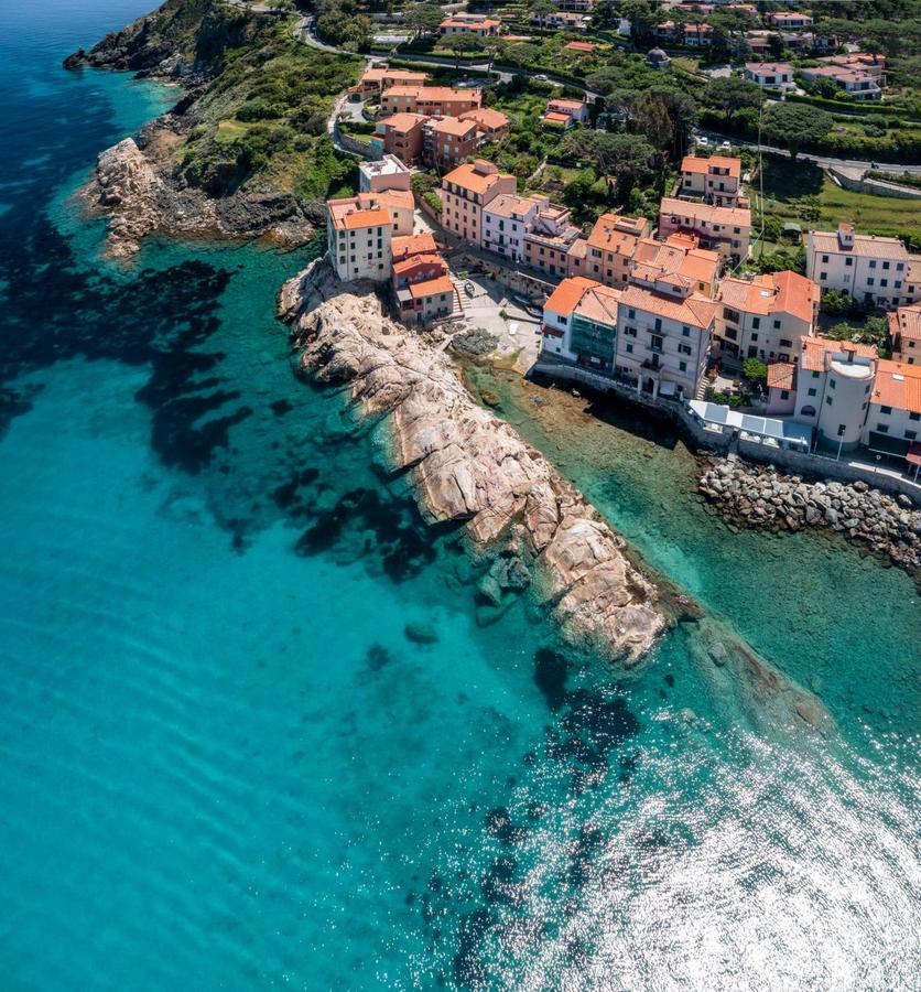 Borgo dell'Isola d'Elba affacciato sul mare, con le case colorate e gli scogli davanti